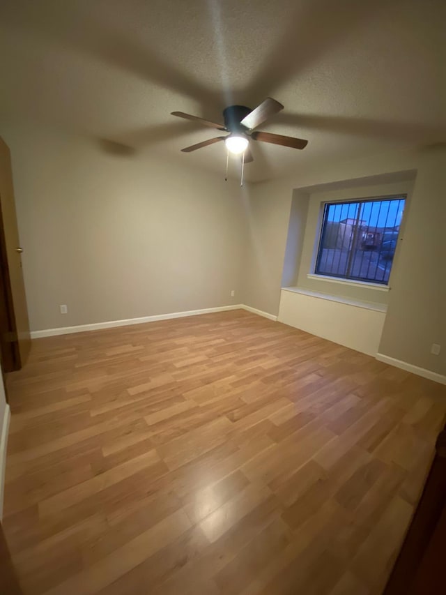 unfurnished room featuring a ceiling fan, baseboards, and light wood-style flooring