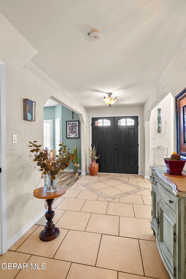 1829 Paseo Real Cir, El Paso, TX 79936 - entrance foyer with baseboards, arched walkways, light tile patterned floors, and a healthy amount of sunlight