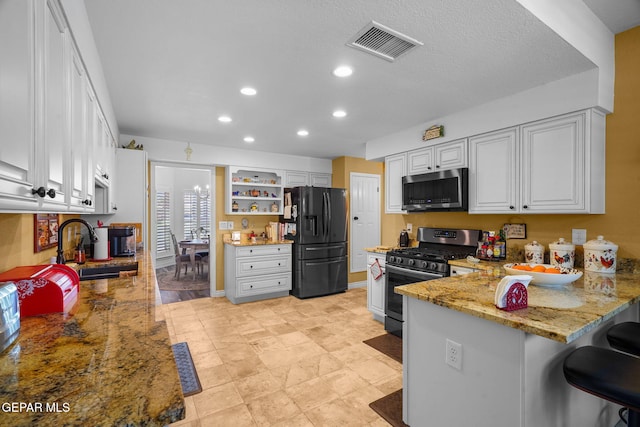 1829 Paseo Real Cir, El Paso, TX 79936 - kitchen featuring visible vents, a peninsula, light stone counters, a sink, and stainless steel appliances