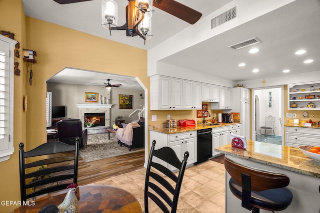 1829 Paseo Real Cir, El Paso, TX 79936 - kitchen featuring black dishwasher, ceiling fan, visible vents, and a stone fireplace