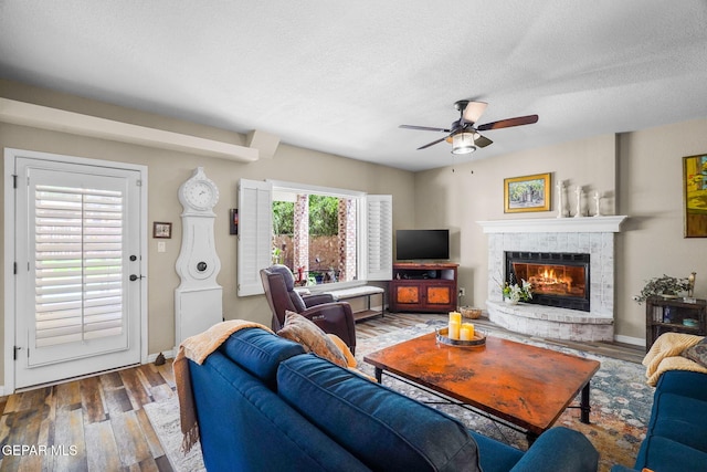 1829 Paseo Real Cir, El Paso, TX 79936 - living area featuring wood finished floors, baseboards, ceiling fan, a textured ceiling, and a tiled fireplace