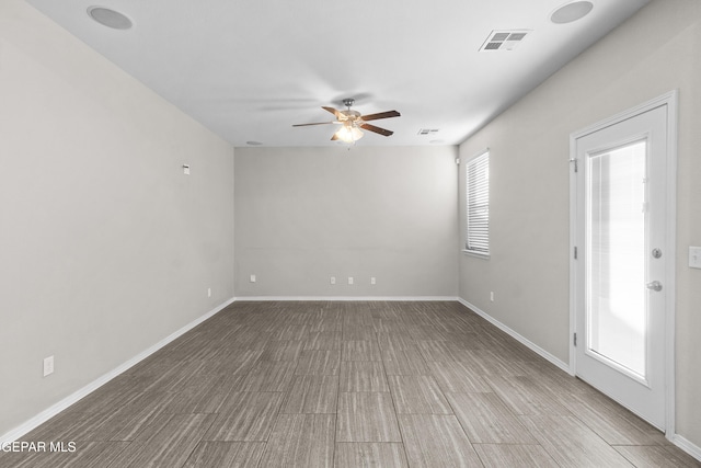 unfurnished room with baseboards, a ceiling fan, wood finished floors, and visible vents