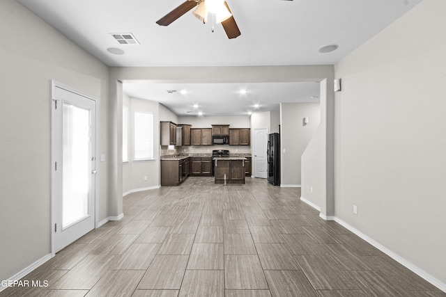unfurnished living room featuring baseboards, ceiling fan, wood finish floors, and visible vents