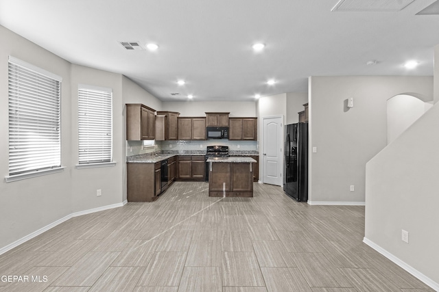 kitchen with baseboards, visible vents, black appliances, and a center island