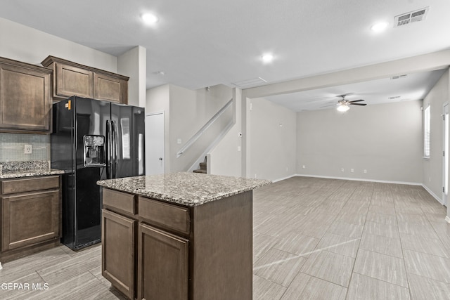 kitchen with light stone countertops, a ceiling fan, backsplash, visible vents, and black fridge with ice dispenser