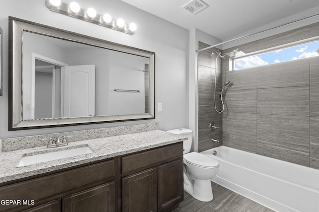 bathroom with shower / bathing tub combination, visible vents, wood finished floors, vanity, and toilet