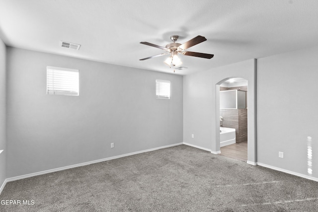 unfurnished bedroom with arched walkways, baseboards, carpet, and visible vents