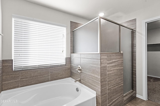 bathroom with a shower stall and a bath