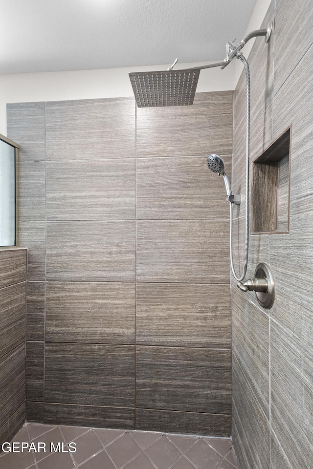 full bathroom featuring tile patterned flooring and a tile shower