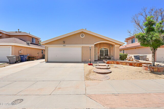 ranch-style house with a garage, stucco siding, and concrete driveway