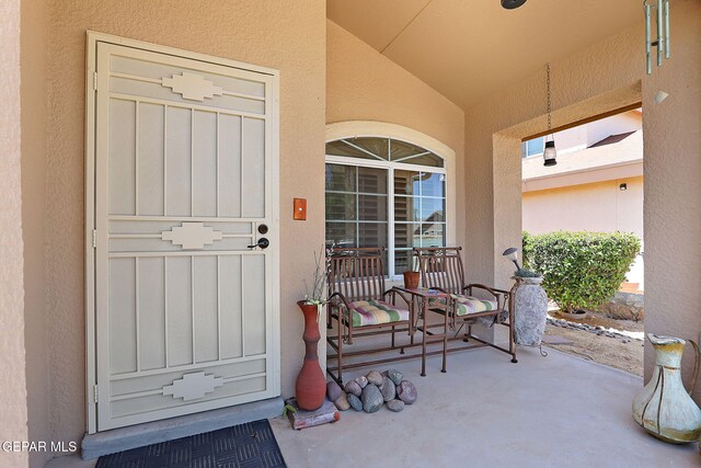 view of exterior entry with a porch and stucco siding