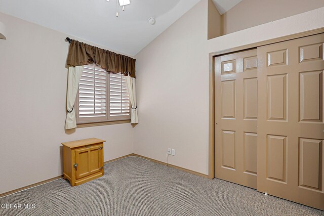 unfurnished bedroom featuring baseboards, light carpet, a closet, and lofted ceiling
