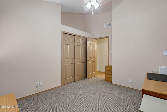 unfurnished bedroom featuring a high ceiling, light carpet, baseboards, visible vents, and a closet