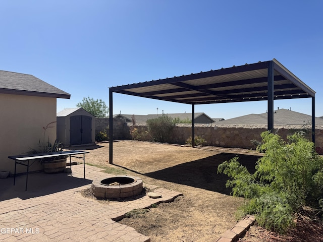 view of yard with a storage shed, an outdoor structure, a fenced backyard, an outdoor fire pit, and a patio