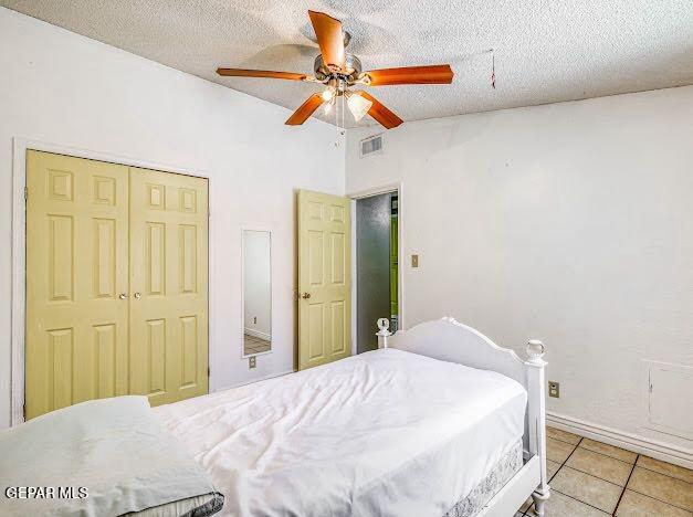 bedroom featuring a ceiling fan, visible vents, vaulted ceiling, light tile patterned floors, and a closet
