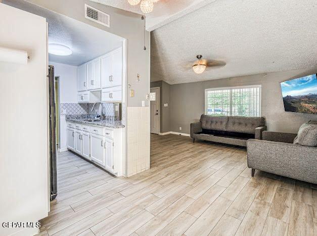 kitchen featuring visible vents, open floor plan, white cabinets, and light wood-type flooring