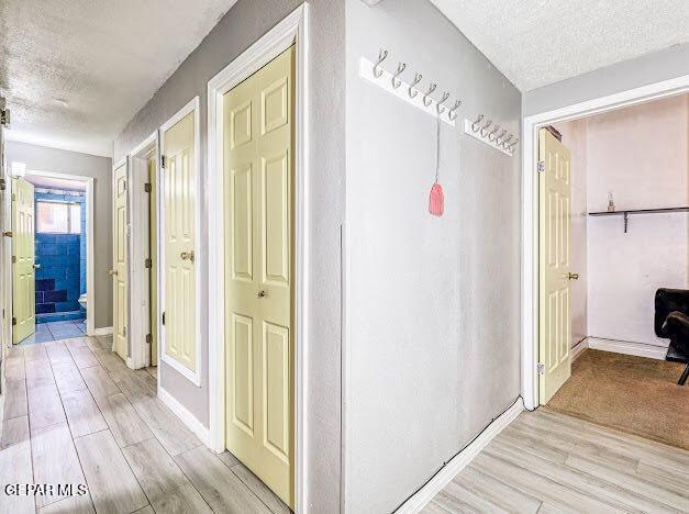 hall with light wood-type flooring and a textured ceiling