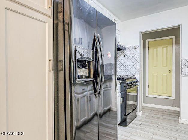 kitchen with backsplash, white cabinets, black appliances, under cabinet range hood, and light wood-style flooring