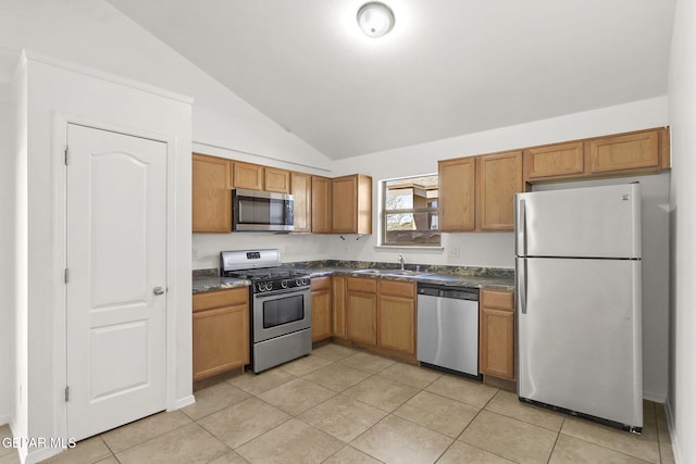 kitchen featuring light tile patterned flooring, dark countertops, appliances with stainless steel finishes, a sink, and lofted ceiling