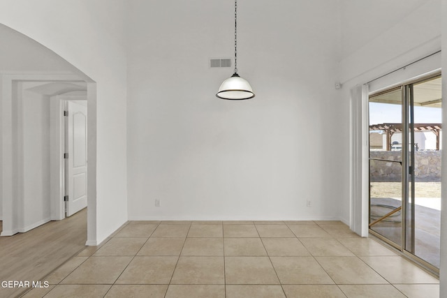 unfurnished dining area featuring baseboards, a high ceiling, light tile patterned flooring, and visible vents