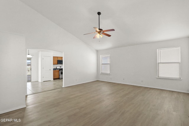 unfurnished living room featuring baseboards, light wood finished floors, ceiling fan, and high vaulted ceiling