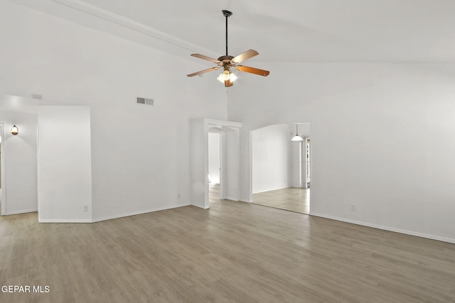 unfurnished living room with a ceiling fan, visible vents, wood finished floors, high vaulted ceiling, and baseboards