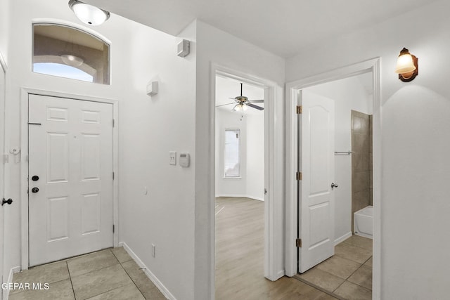 entrance foyer featuring baseboards, a ceiling fan, and light tile patterned floors