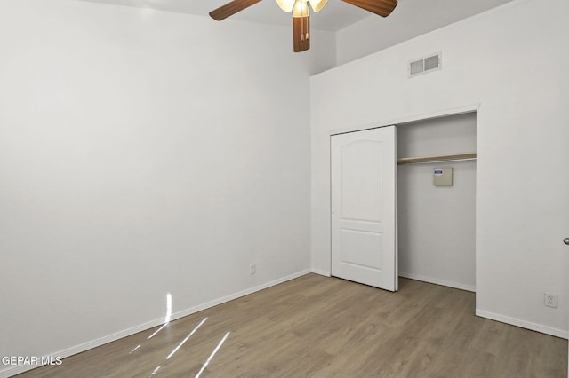 unfurnished bedroom featuring ceiling fan, visible vents, wood finished floors, baseboards, and a closet