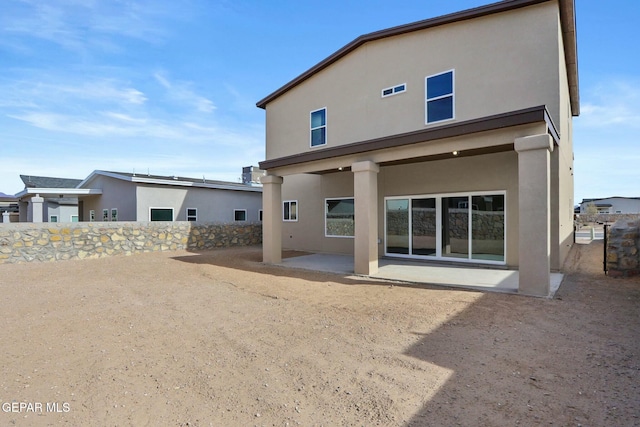 rear view of house featuring a patio, fence, and stucco siding