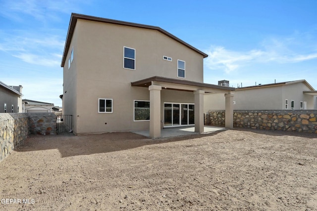 rear view of property with a fenced backyard, stucco siding, and a patio area