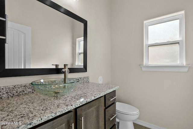 half bath featuring vanity, baseboards, and toilet
