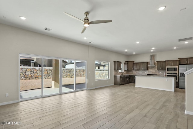 unfurnished living room featuring a sink, light wood-style floors, a ceiling fan, and visible vents