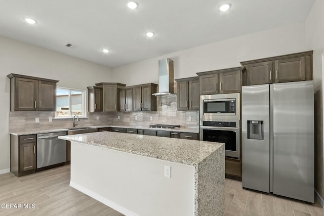 kitchen with dark brown cabinets, a sink, wall chimney exhaust hood, a center island, and stainless steel appliances