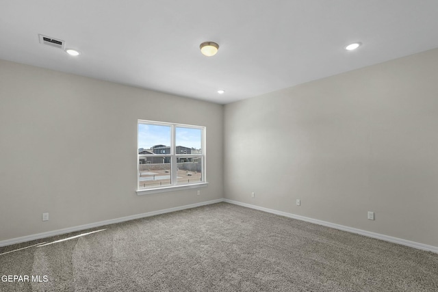 spare room with carpet floors, baseboards, and visible vents