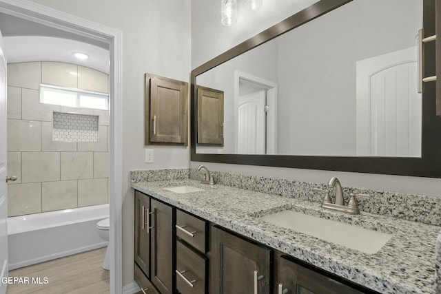 bathroom featuring double vanity, a sink, wood finished floors, and toilet