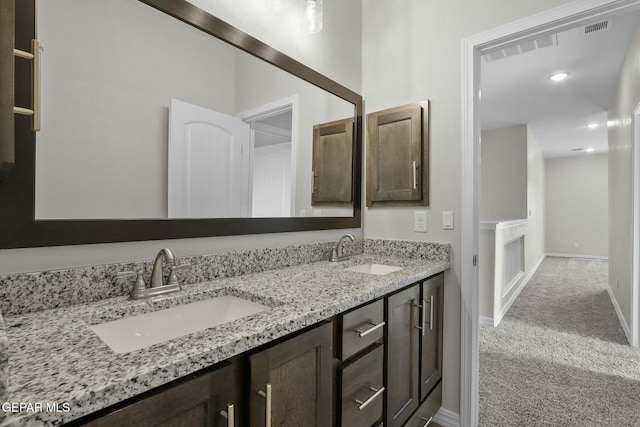 bathroom featuring double vanity, a sink, baseboards, and visible vents