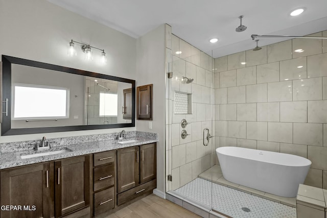 full bathroom with double vanity, a sink, a freestanding tub, and a stall shower