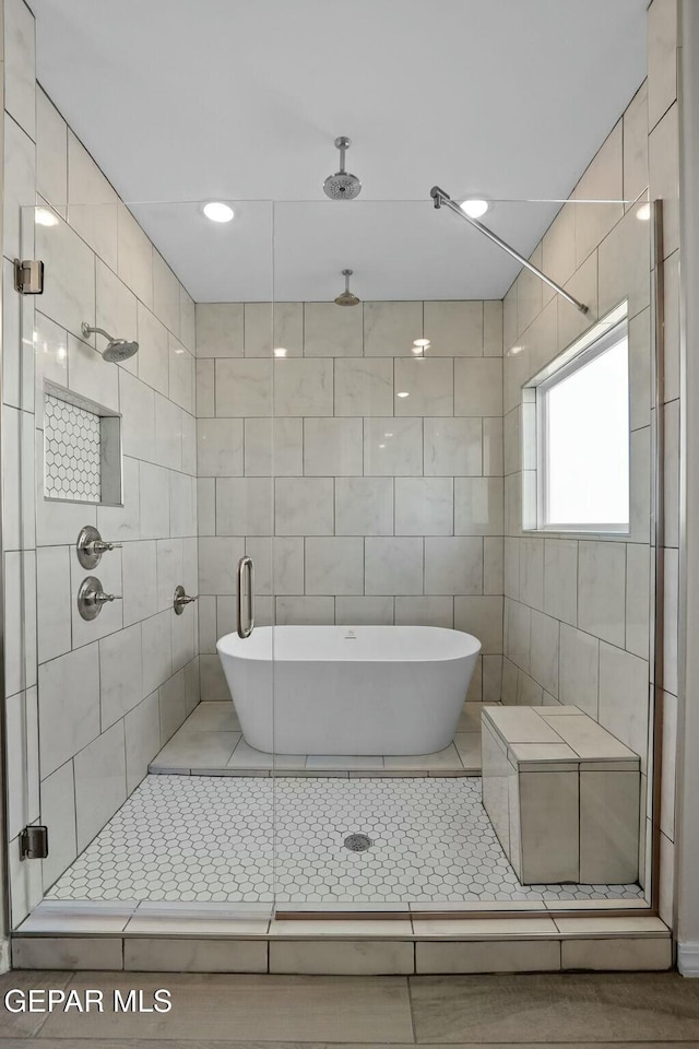 bathroom featuring tile walls, a shower stall, and a soaking tub
