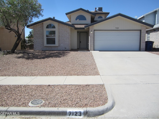 view of front of house featuring brick siding, an attached garage, driveway, and central AC unit