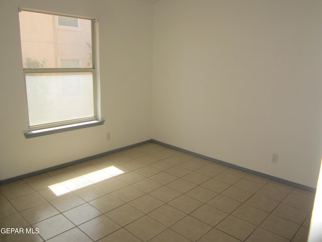 unfurnished room featuring baseboards, a healthy amount of sunlight, and tile patterned flooring