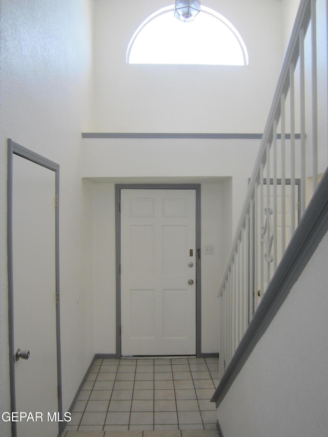 foyer featuring stairway, light tile patterned floors, and a wealth of natural light