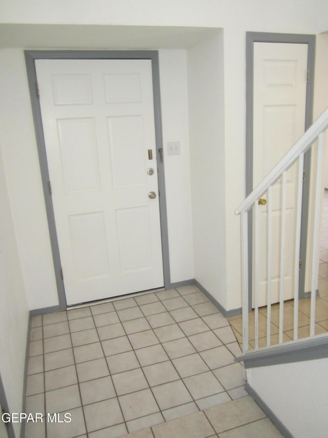 foyer featuring stairs and baseboards