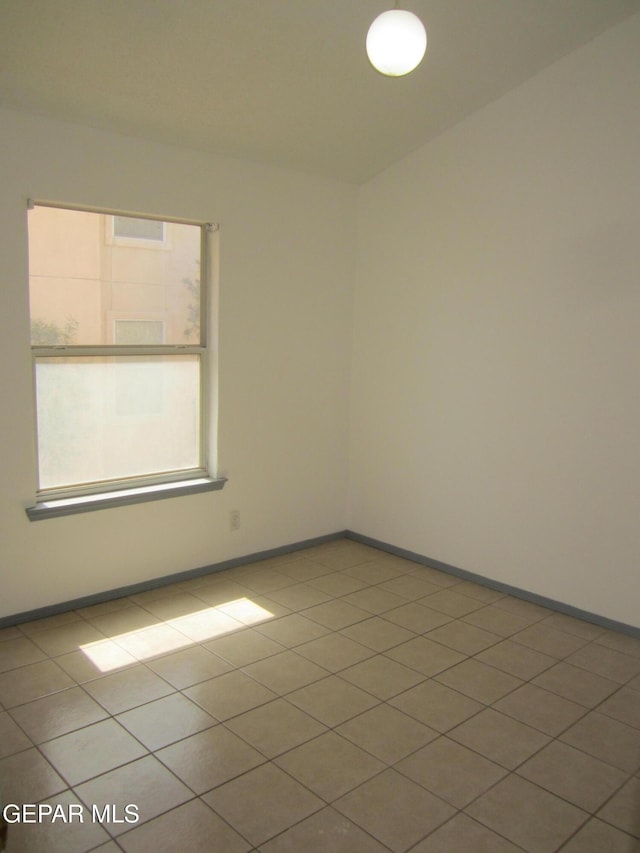 tiled spare room featuring baseboards