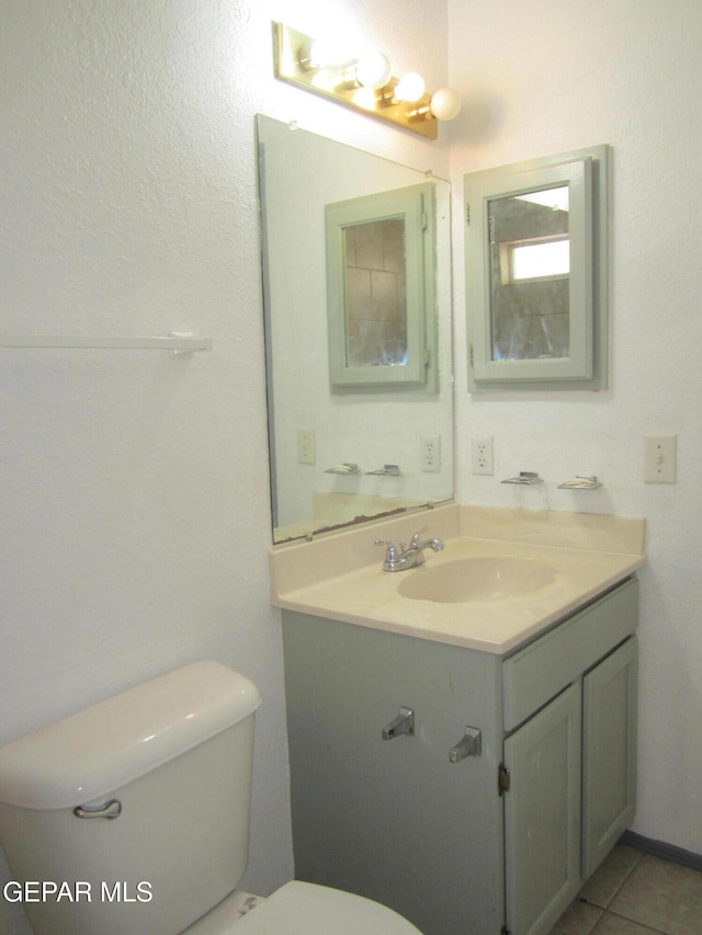 half bathroom featuring vanity, tile patterned flooring, and toilet