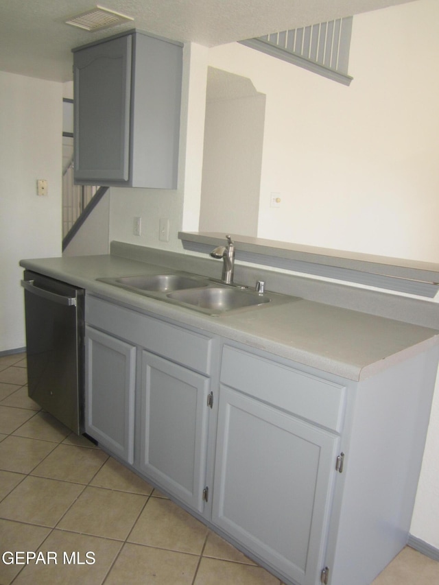 kitchen featuring visible vents, dishwasher, light countertops, a sink, and light tile patterned floors