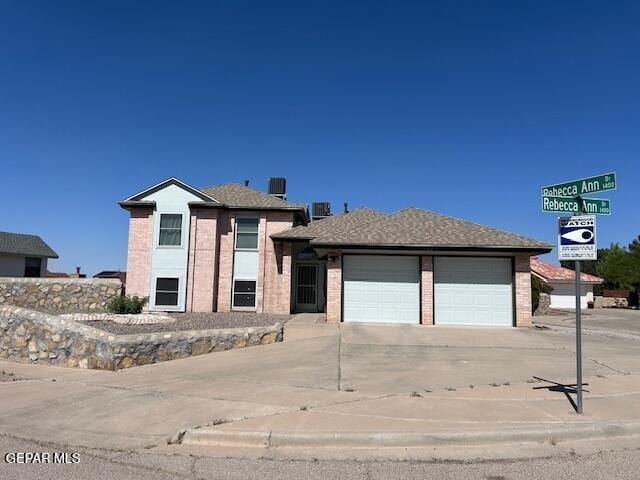 view of front of property featuring central AC unit, an attached garage, concrete driveway, and brick siding