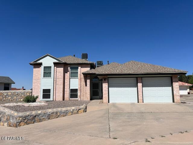 view of front of home with brick siding, driveway, cooling unit, and a garage