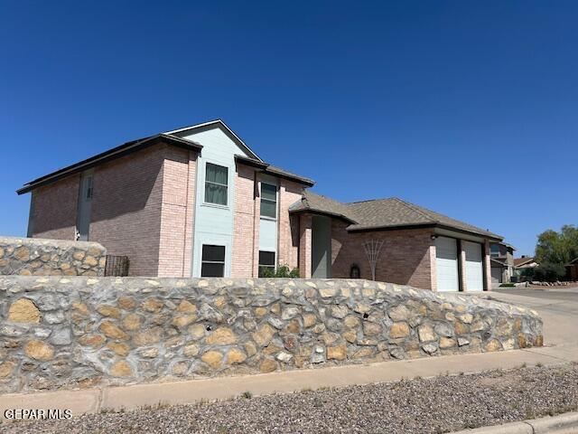 view of side of property featuring brick siding, a garage, and driveway