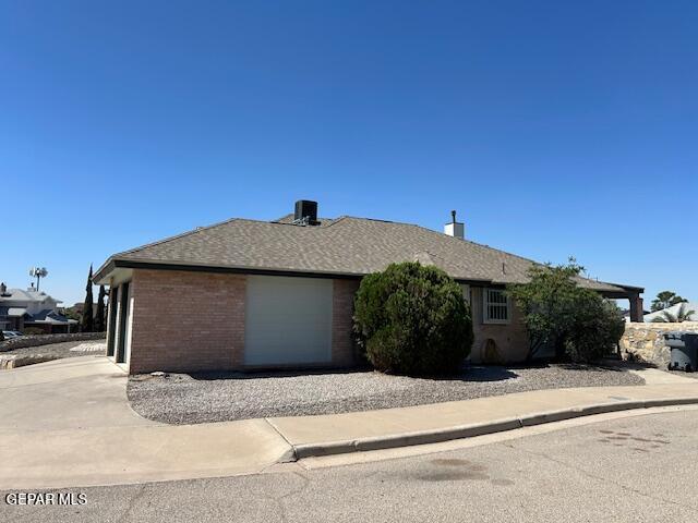 view of side of home featuring brick siding, driveway, and a garage