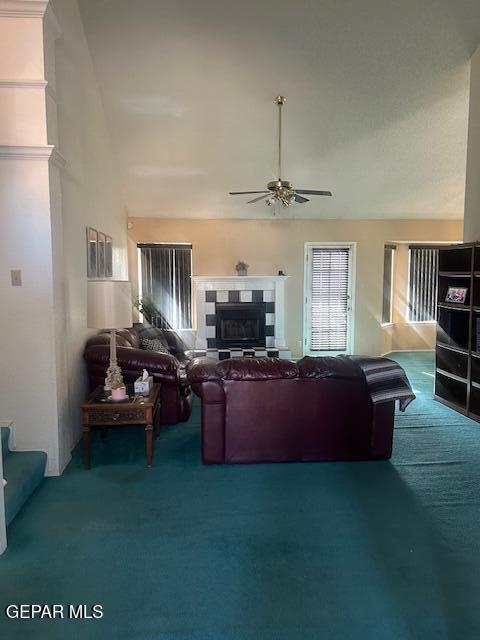 living room with a tiled fireplace, carpet flooring, ceiling fan, and high vaulted ceiling
